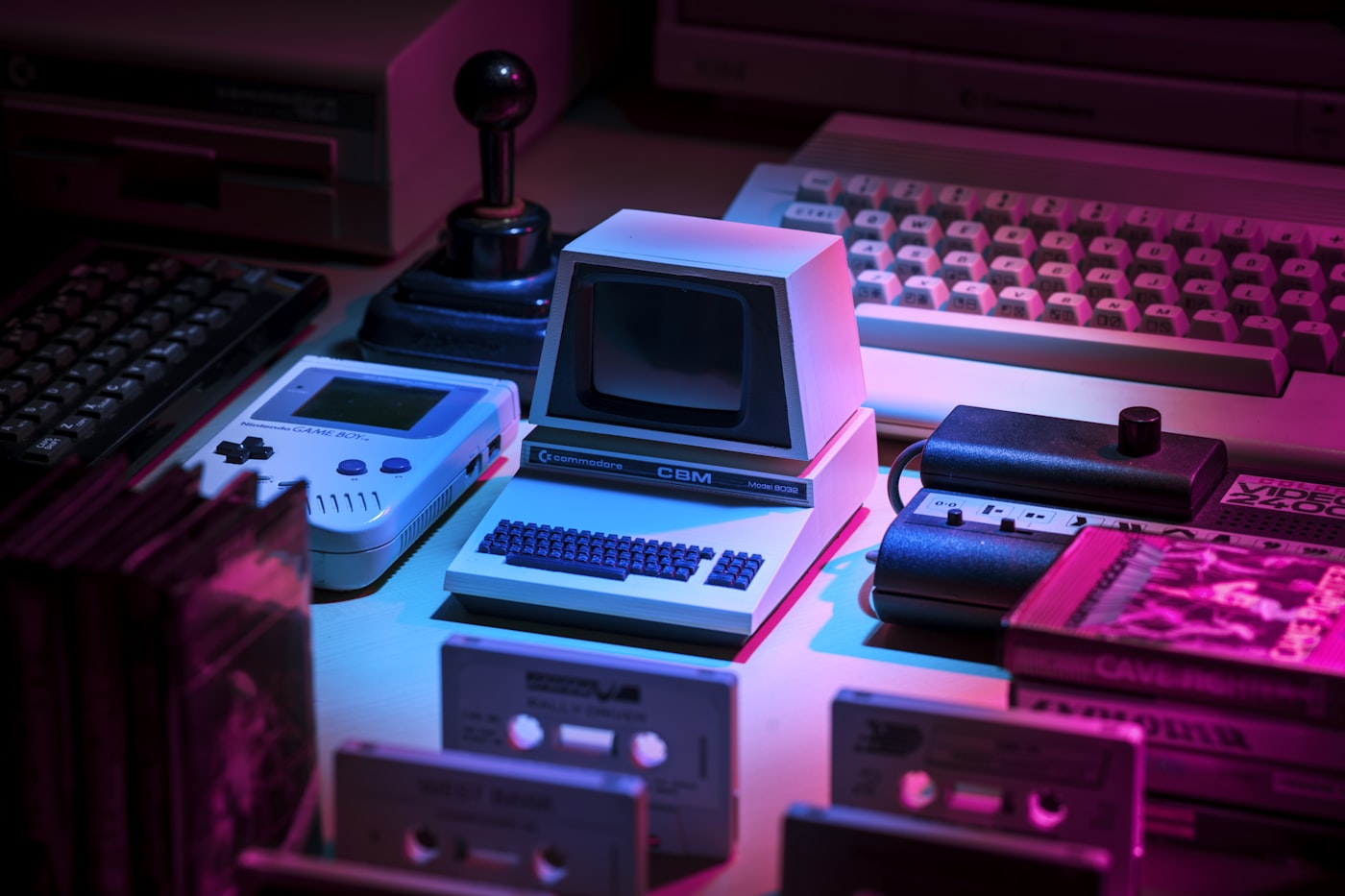 A vintage grey game console and joystick on a magenta background