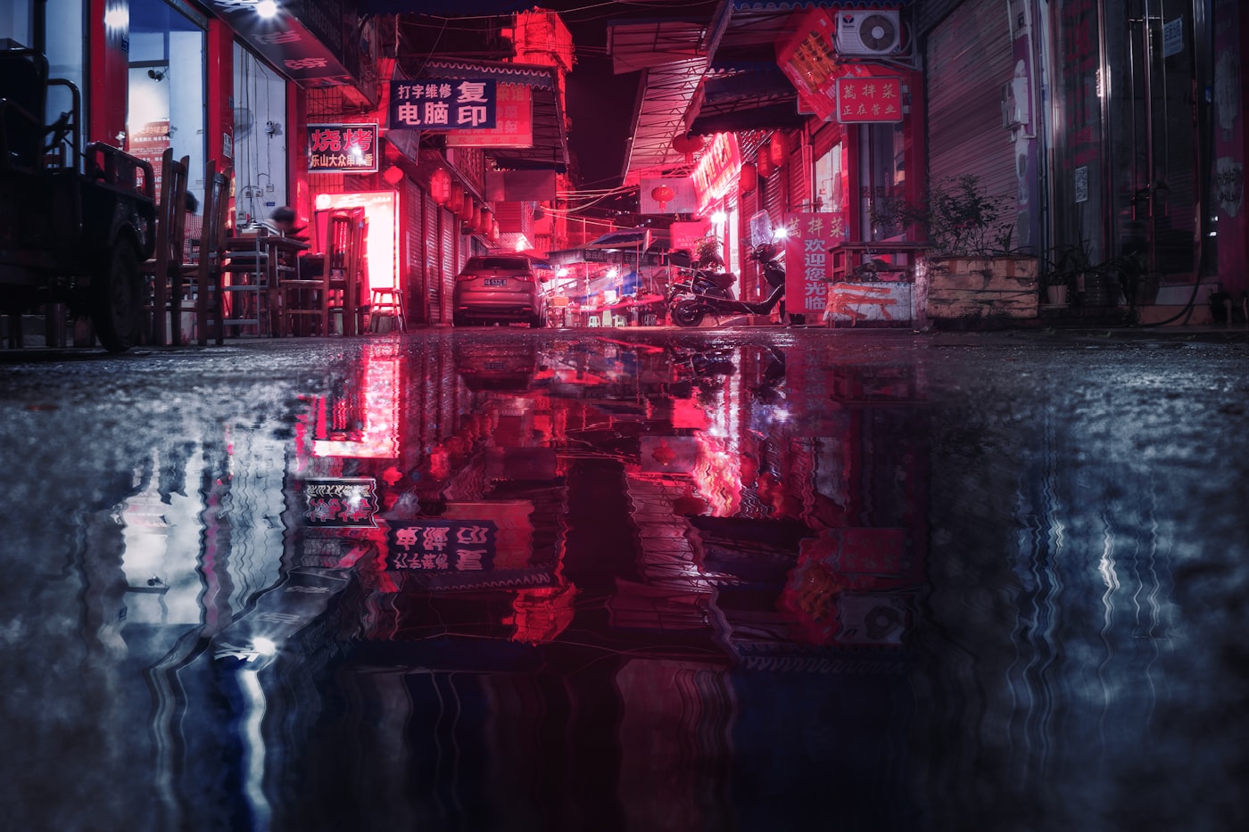 Red neon signs reflected in a street puddle