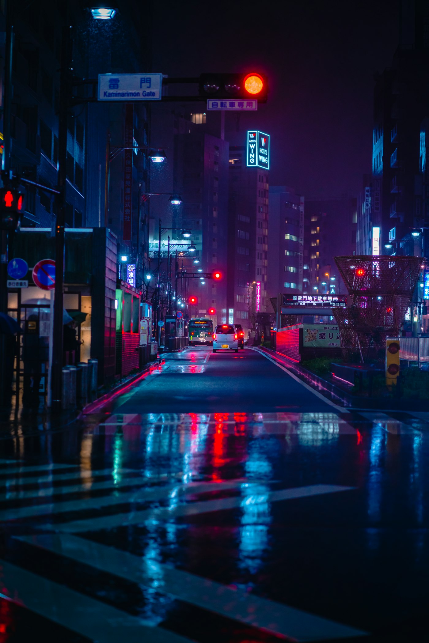 A wet street at night in Tokyo, neon signs reflecting on the pavement