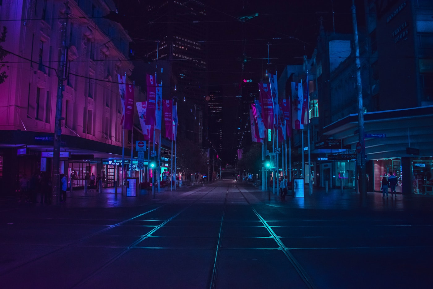 People walking through a neon walkway at night